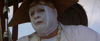 Movie still from “The Island of Dr. Moreau” (1996), directed by Richard Stanley – An old man wearing a white mask and a white hat; Close Up shot, Low angle
