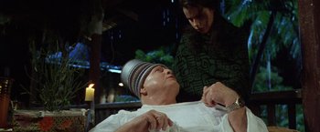 Movie still from “The Island of Dr. Moreau” (1996), directed by Richard Stanley – A woman is shaving a man's head with an electric razor; Medium shot, High angle