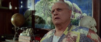 Movie still from “The Island of Dr. Moreau” (1996), directed by Richard Stanley – An older man wearing glasses and a floral shirt; Close Up shot, Low angle