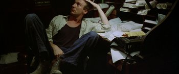 Movie still from “The Island of Dr. Moreau” (1996), directed by Richard Stanley – A man sitting on the ground with a typewriter; Medium shot, High angle