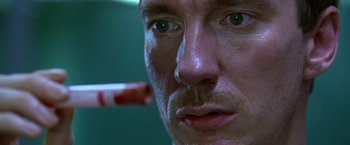 Movie still from “The Island of Dr. Moreau” (1996), directed by Richard Stanley – A man's face with a cigarette in his mouth; Extreme Close Up shot, Low angle