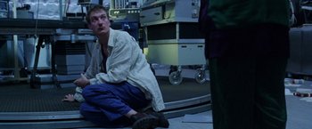 Movie still from “The Island of Dr. Moreau” (1996), directed by Richard Stanley – A man sitting on the ground in a room; Medium shot, Low angle