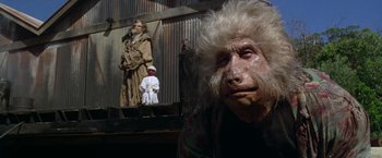 Movie still from “The Island of Dr. Moreau” (1996), directed by Richard Stanley – A man with a white beard is in the background; Close Up shot, Low angle