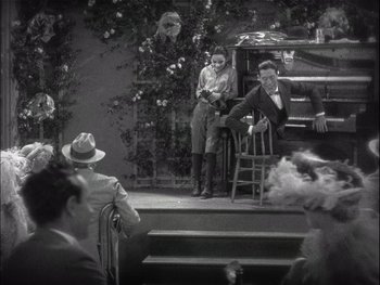 Movie still from “The Jazz Singer” (1927), directed by Alan Crosland – A man and a woman on a stage with a crowd watching; Wide shot, High angle