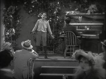 Movie still from “The Jazz Singer” (1927), directed by Alan Crosland – An old photo of a man on a stage singing; Wide shot, High angle