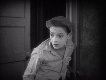 Movie still from “The Jazz Singer” (1927), directed by Alan Crosland – A young boy wearing a hat and a button up shirt; Medium shot, High angle