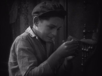 Movie still from “The Jazz Singer” (1927), directed by Alan Crosland – A young man is looking at something in his hands; Close Up shot, High angle