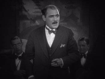 Movie still from “The Jazz Singer” (1927), directed by Alan Crosland – A man in a suit and tie standing next to two other men; Medium shot, Low angle