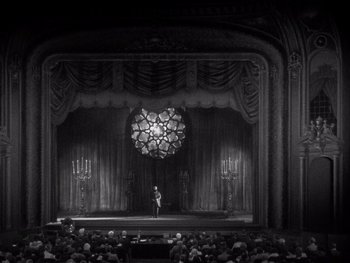 Movie still from “The Jazz Singer” (1927), directed by Alan Crosland – A man standing on a stage in front of an audience; Extreme Wide shot, High angle