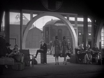 Movie still from “The Jazz Singer” (1927), directed by Alan Crosland – A black and white photo of people waiting at a train station; Extreme Wide shot, High angle