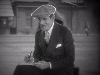 Movie still from “The Jazz Singer” (1927), directed by Alan Crosland – An older man wearing a hat and writing on a piece of paper; Medium shot, High angle
