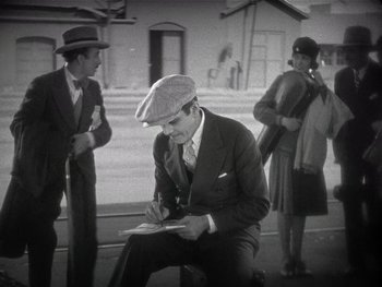 Movie still from “The Jazz Singer” (1927), directed by Alan Crosland – An old photo of a man writing on a piece of paper; Medium shot, High angle