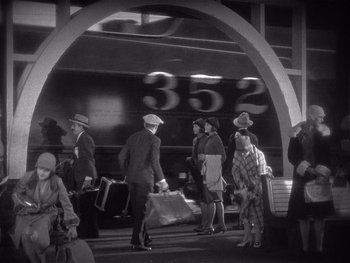Movie still from “The Jazz Singer” (1927), directed by Alan Crosland – A black and white photo of people waiting at a train station; Extreme Wide shot, High angle