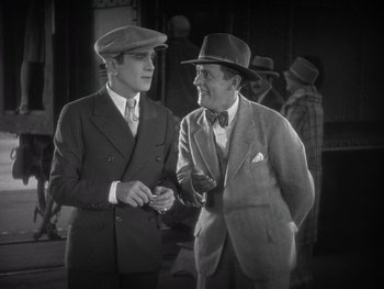 Movie still from “The Jazz Singer” (1927), directed by Alan Crosland – Two men in suits and hats talking to each other; Medium shot, High angle