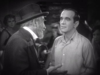 Movie still from “The Jazz Singer” (1927), directed by Alan Crosland – A man in a suit and hat talking to another man in a suit and hat; Medium shot, High angle