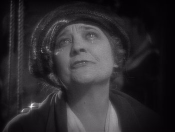 Movie still from “The Jazz Singer” (1927), directed by Alan Crosland – An older woman wearing a black hat and a white shirt; Close Up shot, High angle