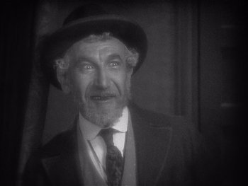 Movie still from “The Jazz Singer” (1927), directed by Alan Crosland – An older man wearing a suit and a hat; Close Up shot, High angle