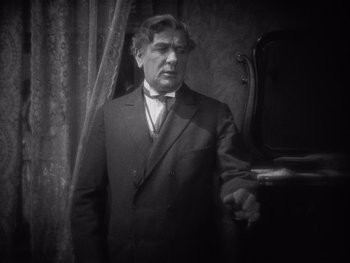 Movie still from “The Jazz Singer” (1927), directed by Alan Crosland – A man in a suit standing in front of a window; Close Up shot, High angle