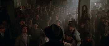 Movie still from “The Journey of Natty Gann” (1985), directed by Jeremy Kagan – A group of people in a room with hats on; Wide shot, High angle