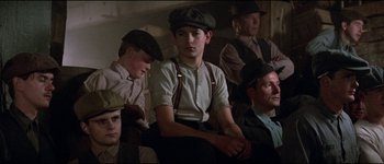 Movie still from “The Journey of Natty Gann” (1985), directed by Jeremy Kagan – A group of men sitting next to each other on a couch; Medium shot, Low angle