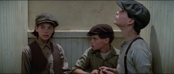 Movie still from “The Journey of Natty Gann” (1985), directed by Jeremy Kagan – A group of young people sitting next to each other on a bench; Medium shot, Low angle
