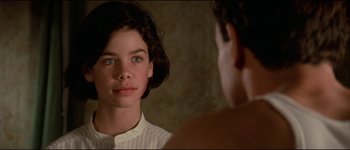 Movie still from “The Journey of Natty Gann” (1985), directed by Jeremy Kagan – A young woman looking into a mirror while standing next to a man; Close Up shot, Over the shoulder angle