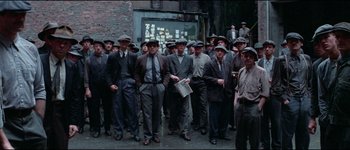 Movie still from “The Journey of Natty Gann” (1985), directed by Jeremy Kagan – A large group of men standing next to each other on the street; Wide shot, High angle