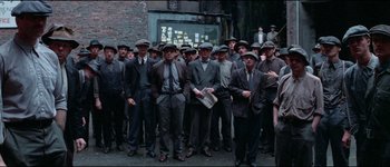 Movie still from “The Journey of Natty Gann” (1985), directed by Jeremy Kagan – A group of men standing next to each other in suits; Wide shot, High angle