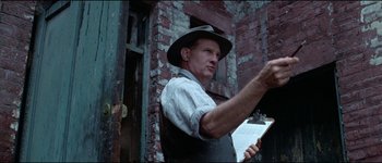 Movie still from “The Journey of Natty Gann” (1985), directed by Jeremy Kagan – A man in an apron and a hat holding a clipboard; Close Up shot, Low angle