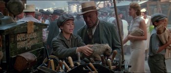 Movie still from “The Journey of Natty Gann” (1985), directed by Jeremy Kagan – A man and a boy looking at wooden objects in a market; Medium shot, Over the shoulder angle