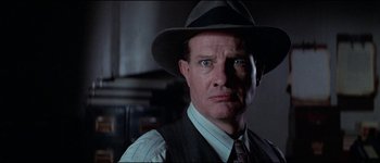 Movie still from “The Journey of Natty Gann” (1985), directed by Jeremy Kagan – A person wearing a suit and hat; Close Up shot, Low angle