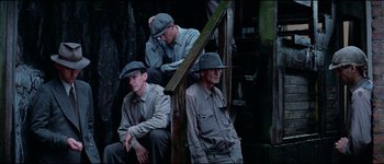 Movie still from “The Journey of Natty Gann” (1985), directed by Jeremy Kagan – A group of men sitting next to each other on steps; Medium shot, Low angle