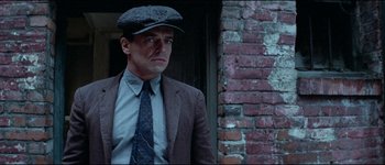 Movie still from “The Journey of Natty Gann” (1985), directed by Jeremy Kagan – A man wearing a hat and a suit standing in front of a brick wall; Close Up shot, Low angle