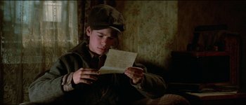 Movie still from “The Journey of Natty Gann” (1985), directed by Jeremy Kagan – A young boy is reading an old letter; Close Up shot, Over the shoulder angle