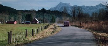 Movie still from “The Journey of Natty Gann” (1985), directed by Jeremy Kagan – A van driving down a road near a field and a barn; Extreme Wide shot, High angle