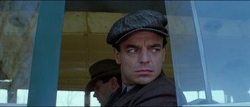 Movie still from “The Journey of Natty Gann” (1985), directed by Jeremy Kagan – A man in a hat and a suit looking at the camera; Close Up shot, Low angle