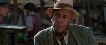 Movie still from “The Journey of Natty Gann” (1985), directed by Jeremy Kagan – An older man wearing a hat and a suit; Close Up shot, Over the shoulder angle