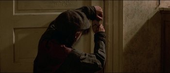 Movie still from “The Journey of Natty Gann” (1985), directed by Jeremy Kagan – A man leaning against a wall with his hands on the side of the wall; Close Up shot, High angle