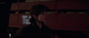 Movie still from “The Journey of Natty Gann” (1985), directed by Jeremy Kagan – A person wearing a hat and a jacket; Close Up shot, Over the shoulder angle