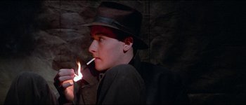 Movie still from “The Journey of Natty Gann” (1985), directed by Jeremy Kagan – A man in a hat is smoking a cigarette; Close Up shot, High angle