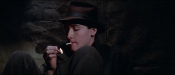 Movie still from “The Journey of Natty Gann” (1985), directed by Jeremy Kagan – A man wearing a hat is lighting a cigarette; Close Up shot, High angle