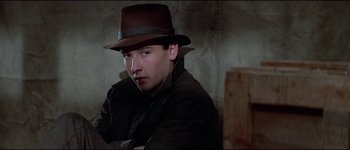 Movie still from “The Journey of Natty Gann” (1985), directed by Jeremy Kagan – A young man wearing a brown hat and a brown jacket; Close Up shot, Over the shoulder angle