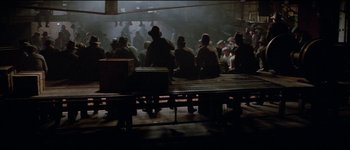 Movie still from “The Journey of Natty Gann” (1985), directed by Jeremy Kagan – A group of men sitting on top of a wooden bench; Wide shot, High angle