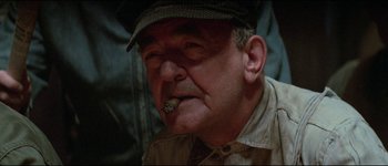Movie still from “The Journey of Natty Gann” (1985), directed by Jeremy Kagan – An older man wearing a hat and smoking a cigar; Close Up shot, Low angle