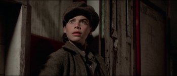 Movie still from “The Journey of Natty Gann” (1985), directed by Jeremy Kagan – A young boy wearing a hat and a coat; Close Up shot, High angle