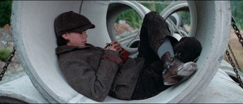 Movie still from “The Journey of Natty Gann” (1985), directed by Jeremy Kagan – A person laying on the ground holding a cell phone; Medium shot, High angle