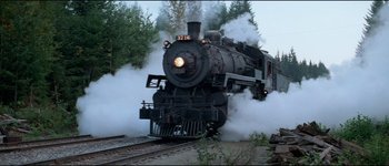 Movie still from “The Journey of Natty Gann” (1985), directed by Jeremy Kagan – A train is coming down the tracks with smoke billowing out of it; Extreme Wide shot, Low angle