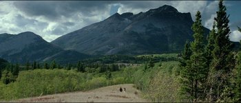 Movie still from “The Journey of Natty Gann” (1985), directed by Jeremy Kagan – A person riding a horse in a field with mountains in the background; Extreme Wide shot, High angle