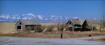 Movie still from “The Journey of Natty Gann” (1985), directed by Jeremy Kagan – A man walking down a road near a house; Extreme Wide shot, High angle
