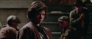 Movie still from “The Journey of Natty Gann” (1985), directed by Jeremy Kagan – A young boy wearing a brown jacket and a brown hat; Close Up shot, Over the shoulder angle